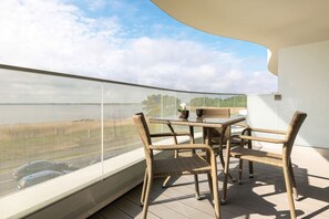 Ein Balkon mit Korbmöbeln, einem Tisch und Stühlen.