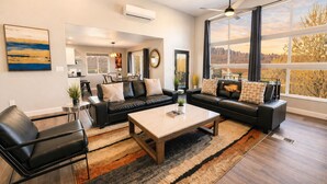 A modern living room with a sofa set, coffee table, and large windows with a view.