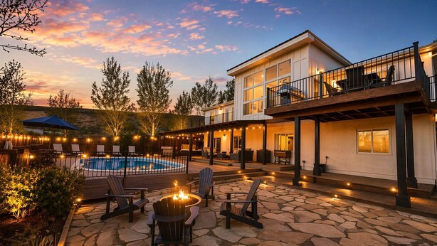 A poolside area with a fire pit, outdoor seating, and a building with a balcony.