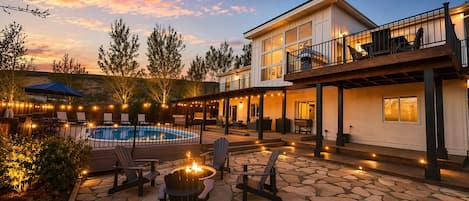 Zona junto a la piscina con un hogar, mobiliario exterior y un edificio con balcón.