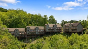 Une rangée de cabanes en bois dotées de balcons, surélevées sur des piliers, et entourées d’une végétation luxuriante.