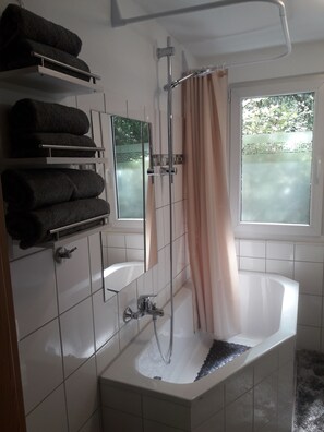 Een bad/douchecombinatie, een haardroger, handdoeken, zeep