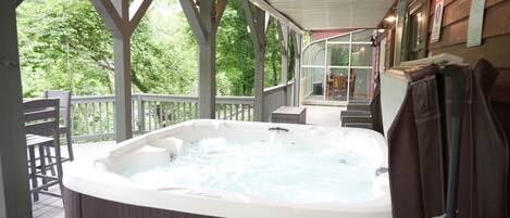 A hot tub on a wooden deck with a view of trees.
