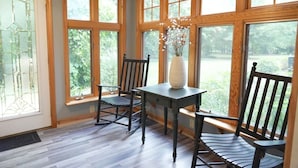 Une pièce avec de grandes fenêtres, une table et deux chaises.