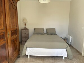 Relax in this serene bedroom with a large bed, a wardrobe, and a small table with a lamp.