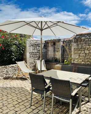 Enjoy dining and socializing in this outdoor patio with a grill area and comfortable seating.