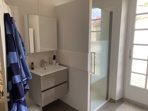 Bathroom features a white vanity, glass shower enclosure, and towel rack.