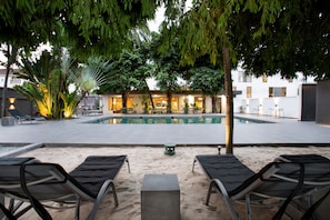 A poolside area with lounge chairs, a small table, and a building in the background.