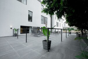A modern outdoor area with a seating area, potted plants, and a railing.