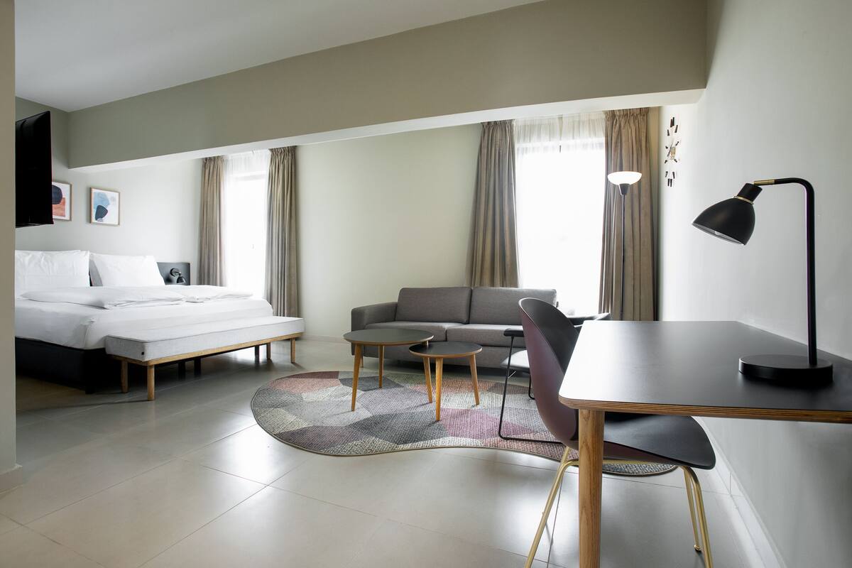 Quarto de hotel com cama, sofá, escrivaninha e cadeira.