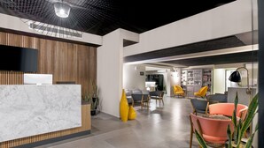 A modern reception area with a marble counter, wooden paneling, and a flat-screen TV. - Nordic Hotel Lagos (Lagos)