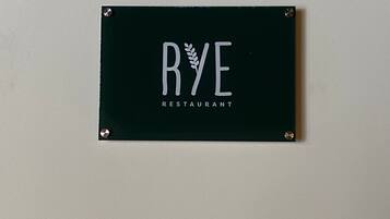 Une enseigne noire avec des lettres blanches indiquant « RYE RESTAURANT ».