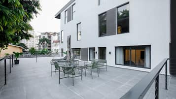 A modern building with a flat roof patio area featuring outdoor seating and a railing.