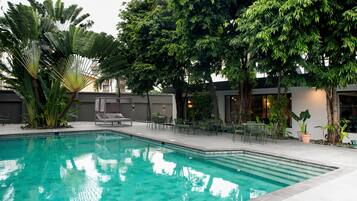 Una piscina al aire libre, sillones reclinables de piscina