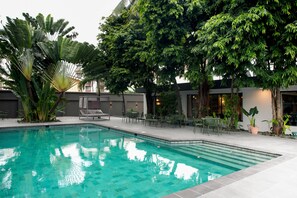 Una piscina al aire libre, sillones reclinables de piscina