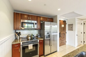 Una cocina moderna con armarios de madera, electrodomésticos de acero inoxidable, un horno Bosch, un microondas y un refrigerador.