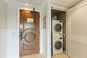 Un cuarto de lavandería con una puerta de madera y dos lavadoras apiladas.