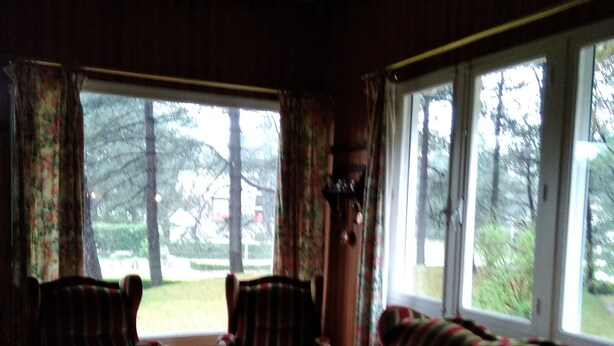 Ein Zimmer mit einem großen Fenster, einem gestreiften Sofa, zwei Sesseln und einem Glastisch.