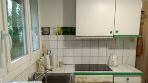 Eine kleine Küche mit Spüle, Waschmaschine und Mikrowelle.
