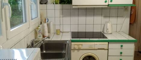 A compact kitchen with a sink, washing machine, and a microwave.