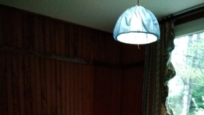 Ein Zimmer mit zwei Betten, einem Nachttisch, einer Lampe und einem Fenster mit Vorhängen.