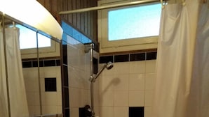 Ein Badezimmer mit Badewanne, Waschbecken, Spiegel und einem Fenster mit Vorhang.