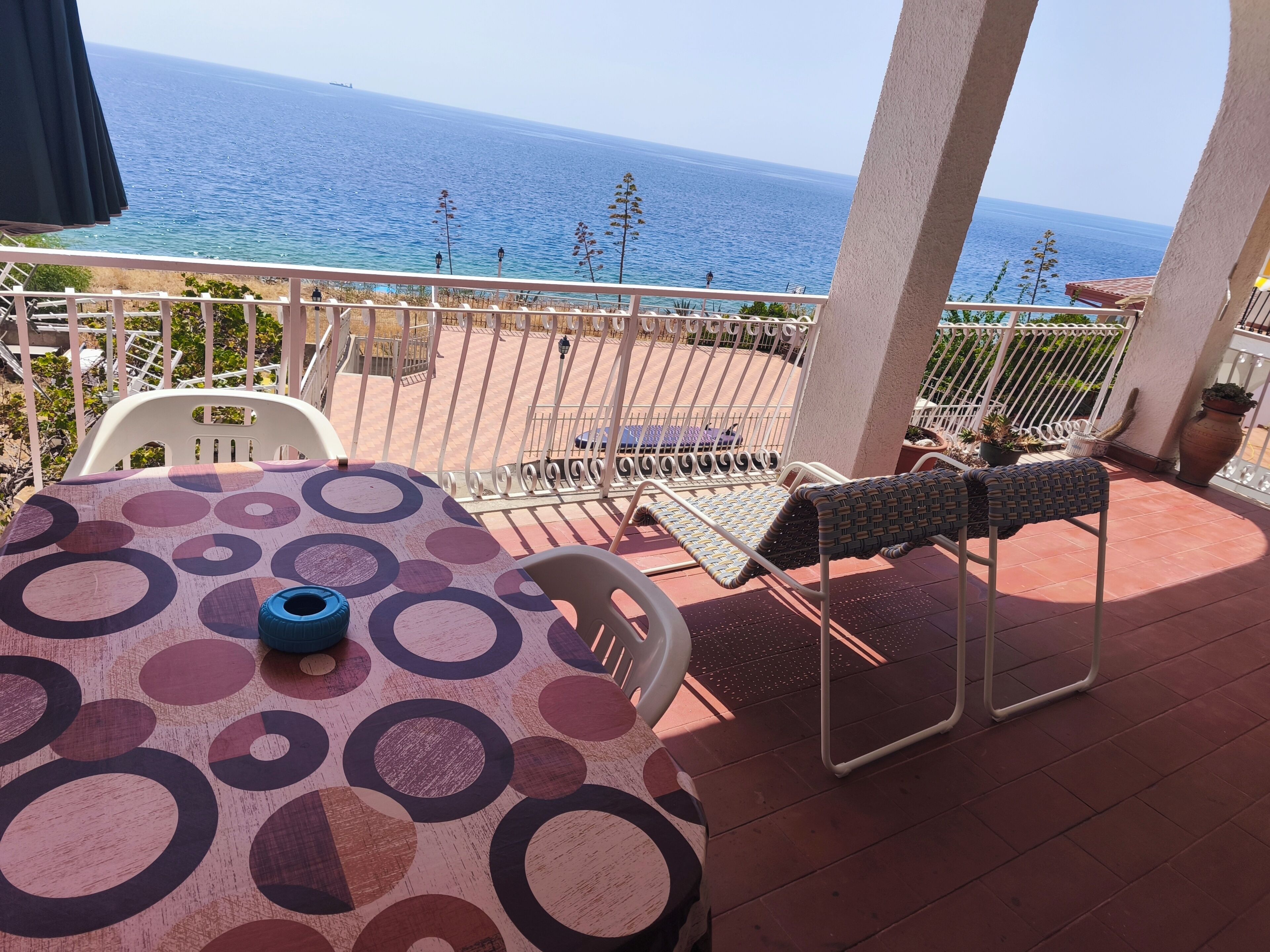 A balcony with a table and chairs, overlooking a body of water.