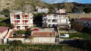 Zona residencial con edificios de varios pisos, un coche rojo estacionado al frente y una camioneta blanca.