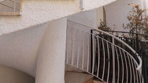 Un edificio residencial de varios niveles con una escalera de caracol y balcones.