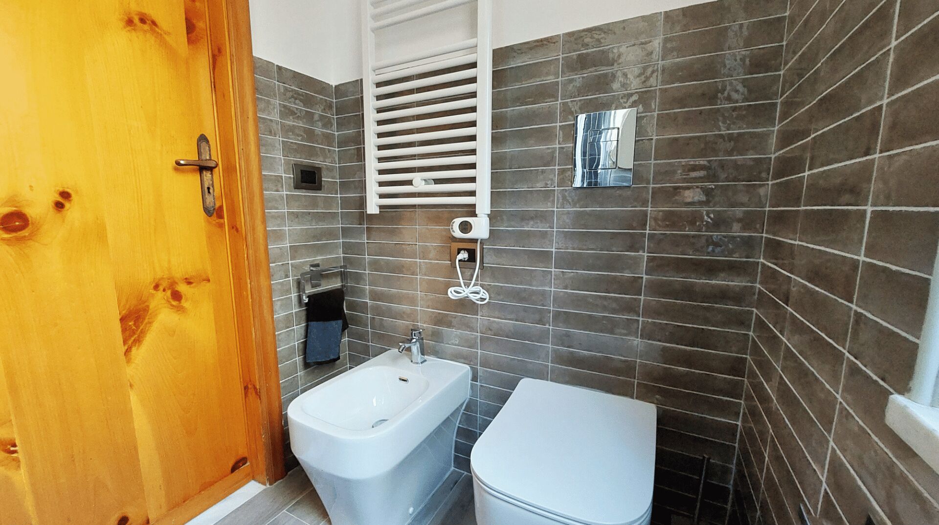 Ein Badezimmer mit Holztür, einer Badewanne, einer Toilette und einem Handtuchhalter.