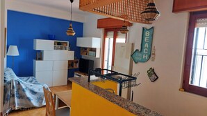 Una cocina compacta con armarios blancos, encimera de granito y un perchero.