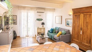Een gezellige woonkamer met een bank, een houten kast en een eethoek met een betegelde tafel.
