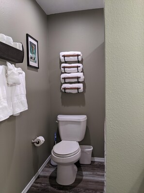 A small bathroom with a toilet, a sink, and a towel rack with multiple towels. - Lee's Lane (Branson)