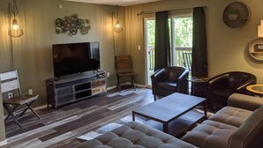 A living room with a flat-screen TV, a sofa, a coffee table, and a fireplace. - Lee's Lane (Branson)