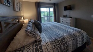 Une chambre à coucher avec un lit, une télévision, une fenêtre et une commode.