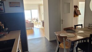A spacious living area with a dining table, chairs, and a kitchen area with a sink and countertop.
