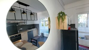 A modern kitchen with black cabinets, a black countertop, and pendant lights. There is a window with a view of greenery outside.