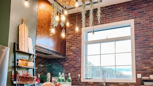 Una cocina moderna con pared de ladrillo, armarios de madera, un ventanal grande e lámparas colgantes.