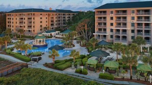 A resort with multiple buildings, a central pool, and outdoor seating areas. - Marriott's Ocean Front Barony Beach Club Resort Hilton Head, SC (Hilton Head Island)