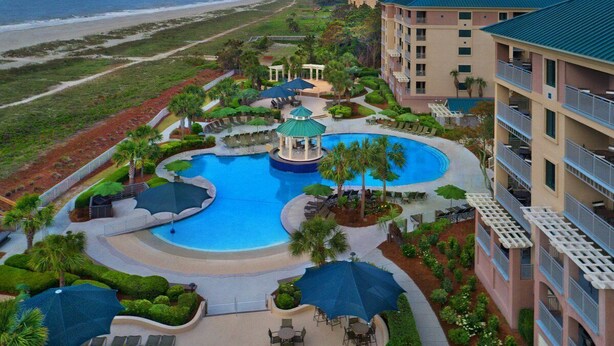 A resort with a large central pool, a beach view, and multiple buildings with balconies. - Marriott's Ocean Front Barony Beach Club Resort Hilton Head, SC (Hilton Head Island)