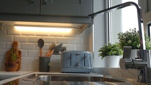 Uma cozinha moderna com armários cinza, uma pia de aço inoxidável e uma torradeira vintage Kenwood.