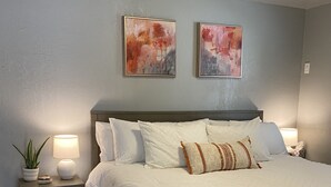 A neatly arranged bedroom with a large bed, two bedside tables with lamps, a potted plant, and a patterned rug. - East Main Downtown Bungalow  (Ashland)