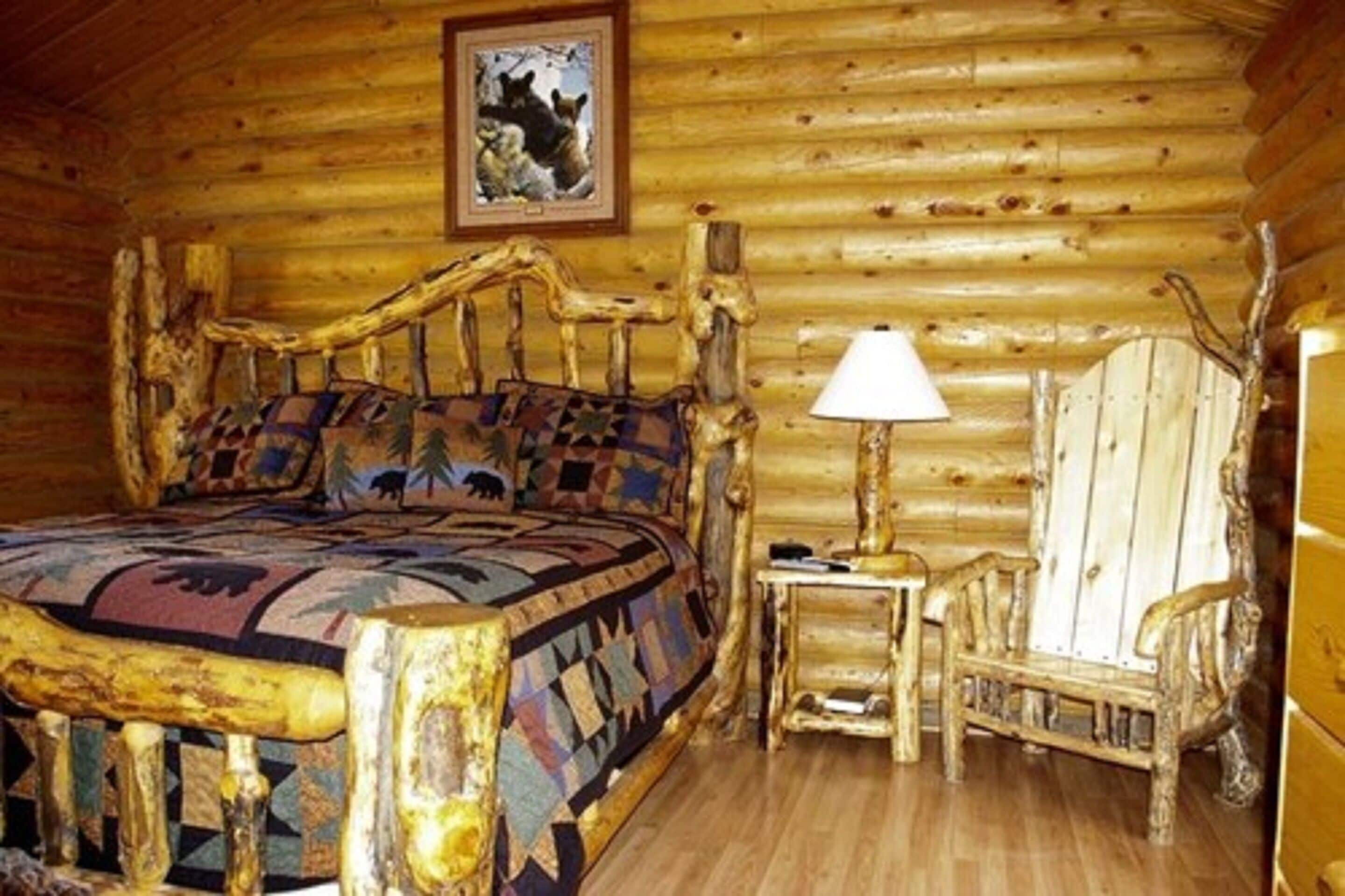 A log cabin room with a wooden bed, a small table, and a chair.