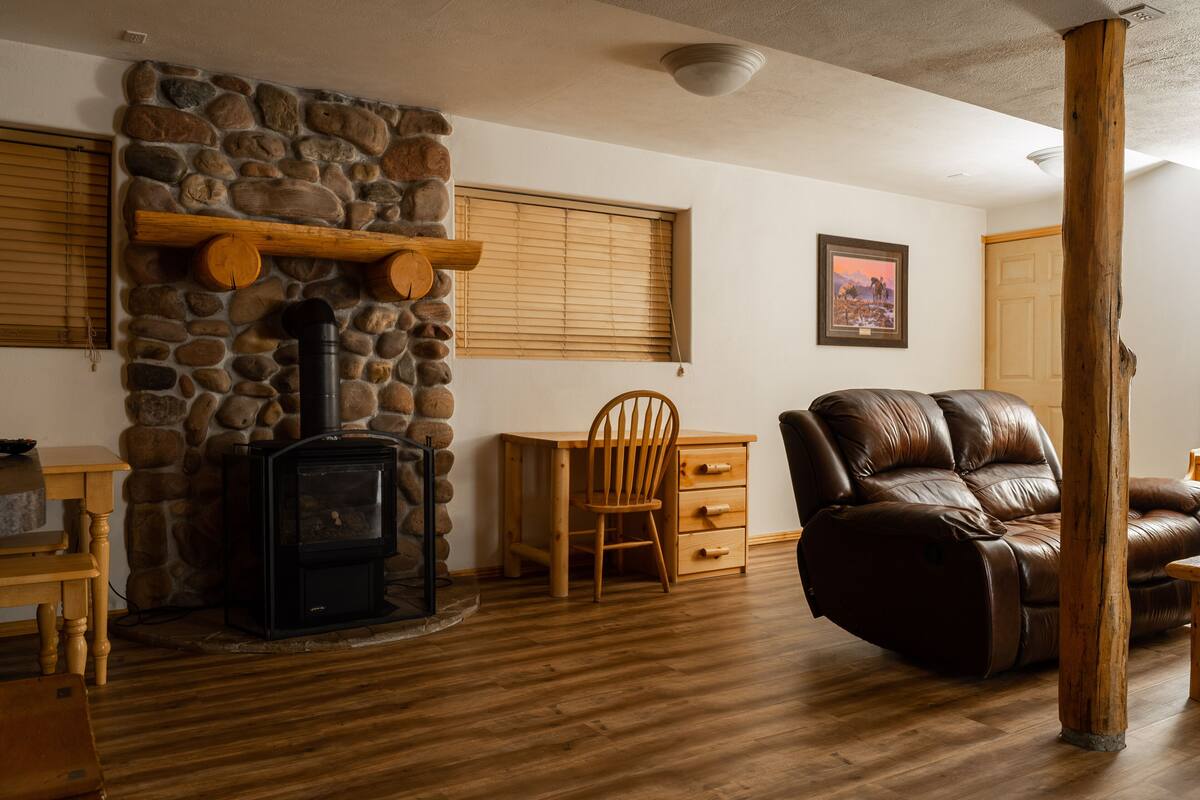 Una sala de estar acogedora con chimenea de piedra, muebles de madera y un sillón de cuero reclinable.