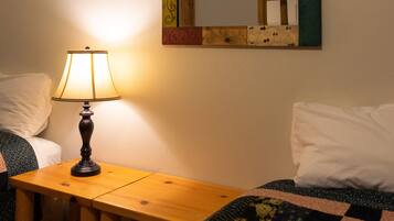 A bedroom with a bed, a bedside table with a lamp, and a mirror on the wall.