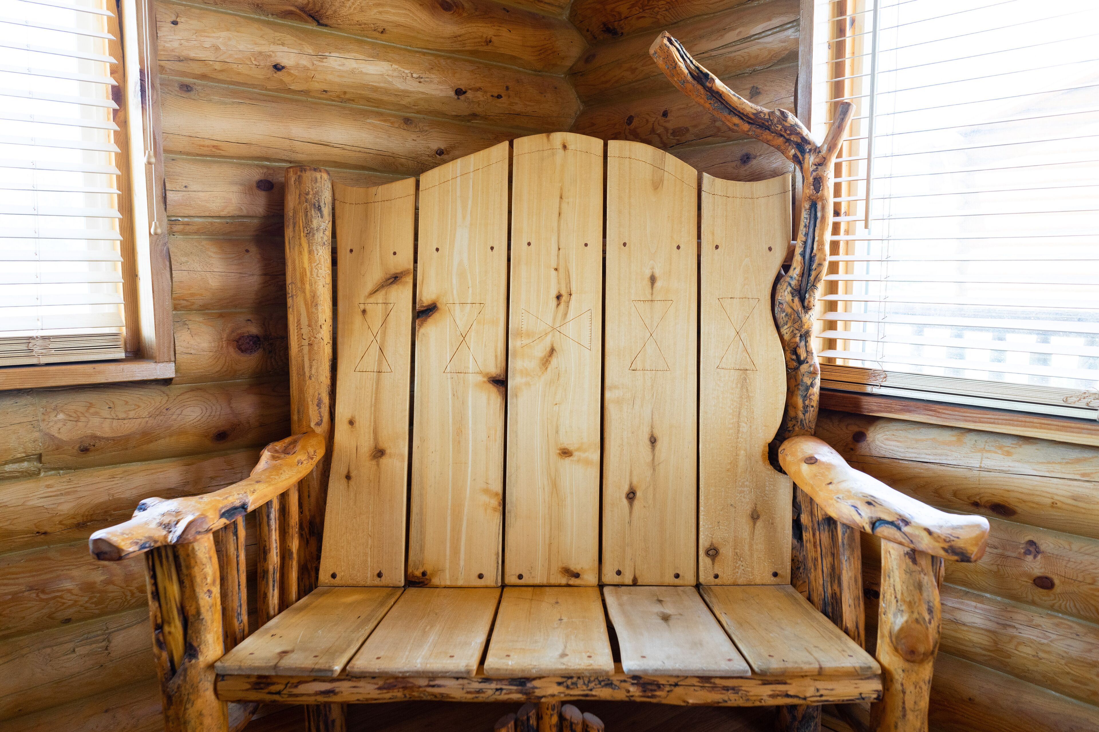 L’intérieur d’un chalet en bois, avec un banc en bois rustique et une grande fenêtre dotée de stores.