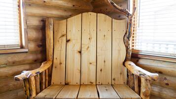 L’intérieur d’un chalet en bois, avec un banc en bois rustique et une grande fenêtre dotée de stores.