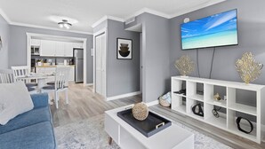 A modern living room with a flat-screen TV, a white entertainment unit, and a blue sofa.