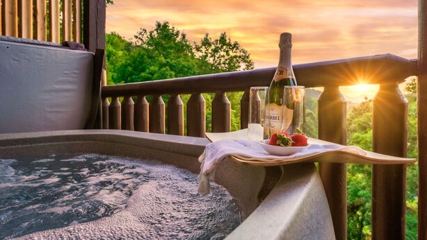 Ein Whirlpool mit einer Weinflasche und Erdbeeren auf einem Tablett, mit Blick auf einen Sonnenuntergang.