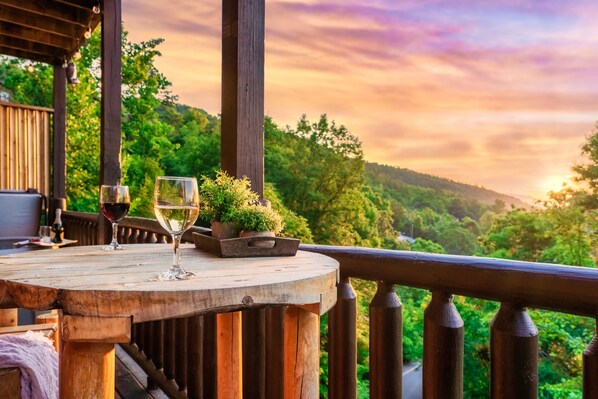 A wooden deck with a table, two wine glasses, and a potted plant.